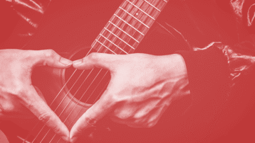 A musician forming a heart shape with their hands over an acoustic guitar, symbolizing love for music on Valentine’s Day.