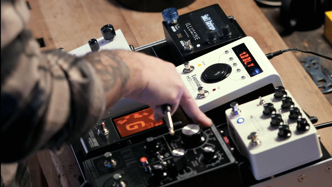 Close-up of guitarist adjusting guitar pedalboard with multiple effects pedals in a studio setup: Pedalboard Basics: How to Set Up and Organize Your Effects Chain
