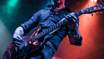 Guitarist playing an electric guitar live on stage with dramatic lighting – focus on guitar riffs
