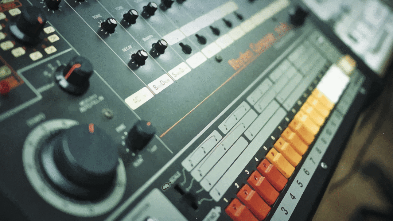 808 day: Close-up view of Roland TR-808 drum machine featuring colorful step-sequencer buttons and analog controls.