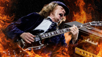 Angus Young of AC/DC playing guitar in front of Marshall amp with flames in background