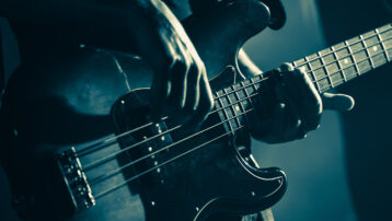 Close-up of a bassist playing live on stage, featured in “The Best Bass Solos in Music History” blog