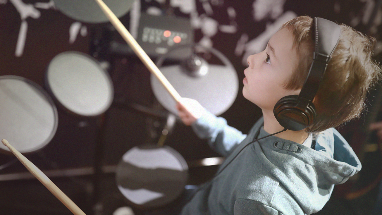 Young drummer playing an electronic drum kit while wearing headphones