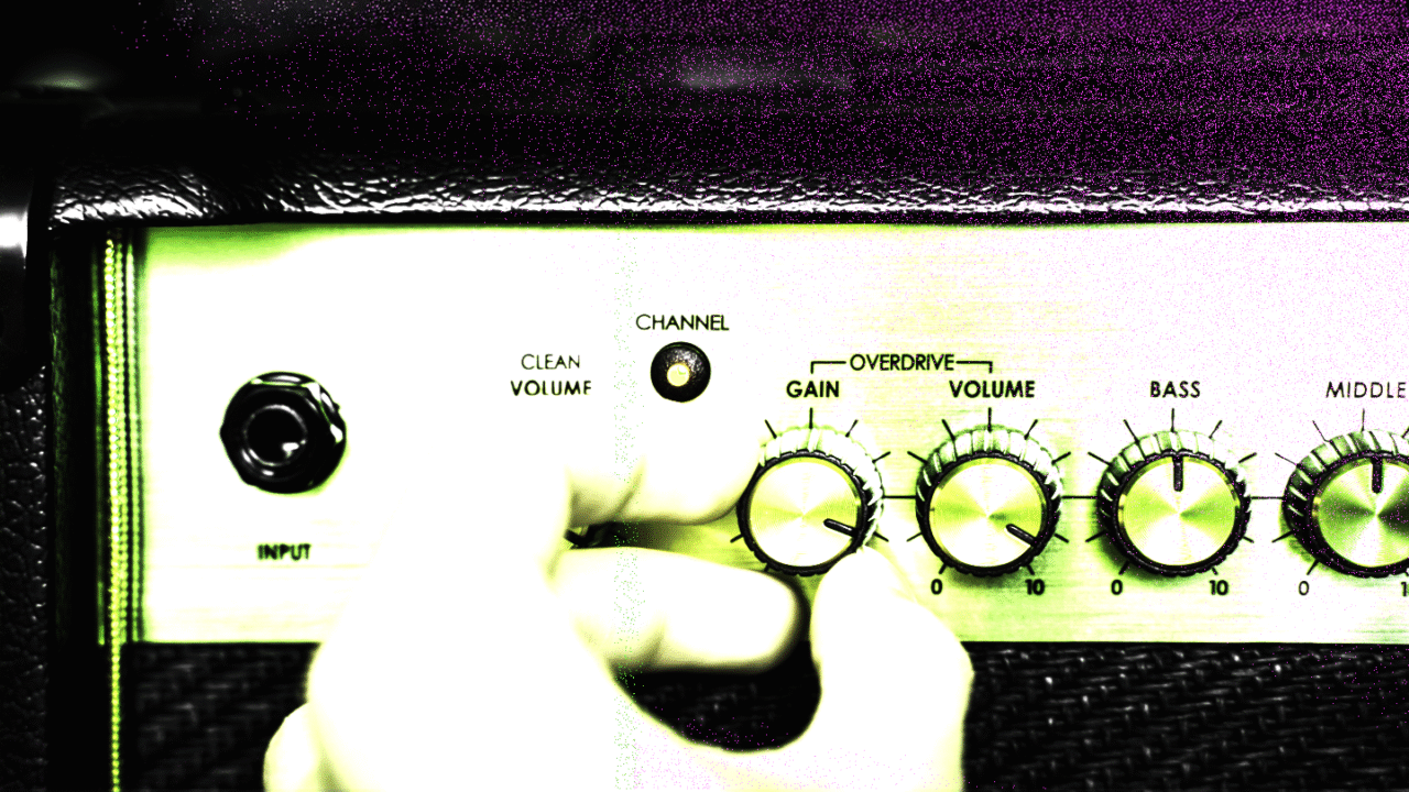 Close-up of a guitar amp with gain and volume knobs being adjusted, representing overdrive pedal history