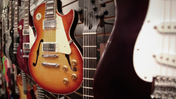 A close-up view of several electric guitars, including Les Paul and Stratocaster styles, lined up in a music store - ideal for beginners exploring their first instrument.