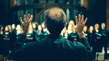 Choir director leading singers during rehearsal, illustrating tips for directing a choir and singing in a choir to improve sound, enjoyment and focus