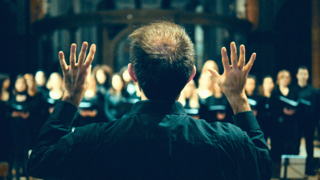 Choir director leading singers during rehearsal, illustrating tips for directing a choir and singing in a choir to improve sound, enjoyment and focus