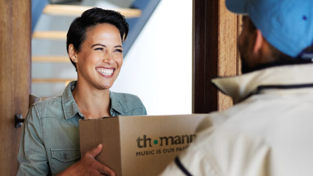 Customer receiving a Thomann delivery at the door – lower shipping costs.