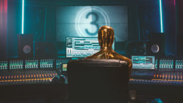 Film composer working in a professional studio with mixing console and digital audio workstation while creating cinematic music for movies