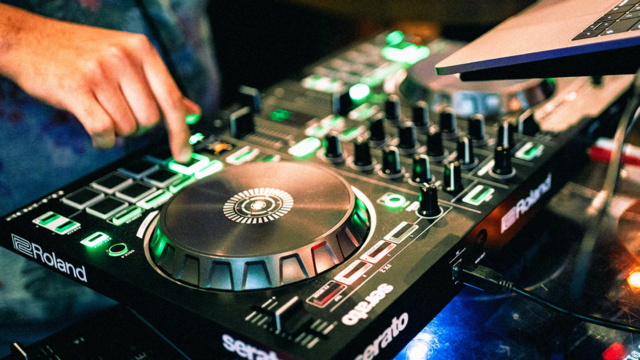 Beginner using a DJ controller with jog wheels and performance pads for mixing music