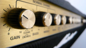 Close-up of the control knobs on a guitar amplifier, showing gain and EQ settings for a beginner guitar amp.