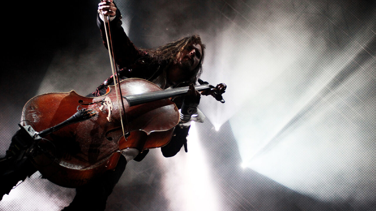 Cellist performing live on stage during a rock concert, showcasing the role of string instruments in modern rock and pop music.