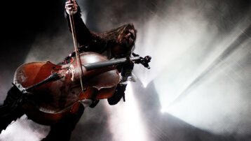 Cellist performing live on stage during a rock concert, showcasing the role of string instruments in modern rock and pop music.