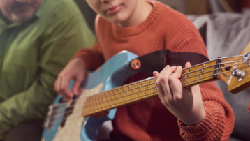 Young musician practising electric bass while learning an instrument