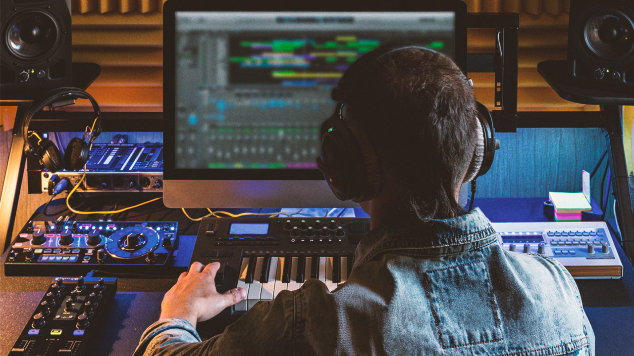 Music producer working at a home studio setup with studio monitors, MIDI keyboard and audio equipment