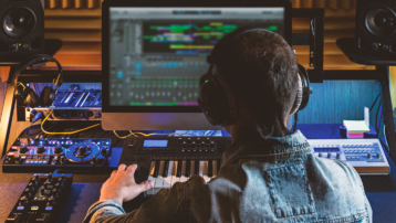 Music producer working at a home studio setup with studio monitors, MIDI keyboard and audio equipment