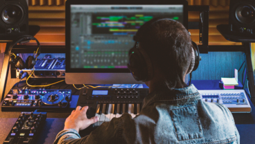 Music producer working at a home studio setup with studio monitors, MIDI keyboard and audio equipment