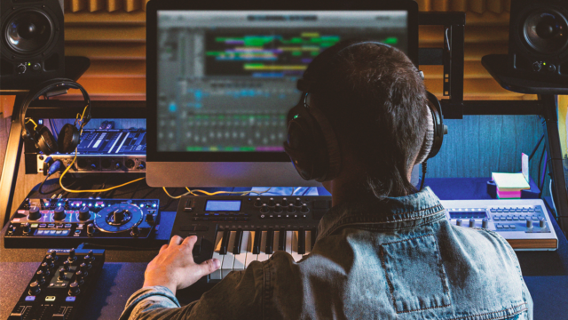 Music producer working at a home studio setup with studio monitors, MIDI keyboard and audio equipment