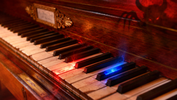 Antique piano keyboard with red and blue glowing keys illustrating the tritone, also known as the Devil's Interval.